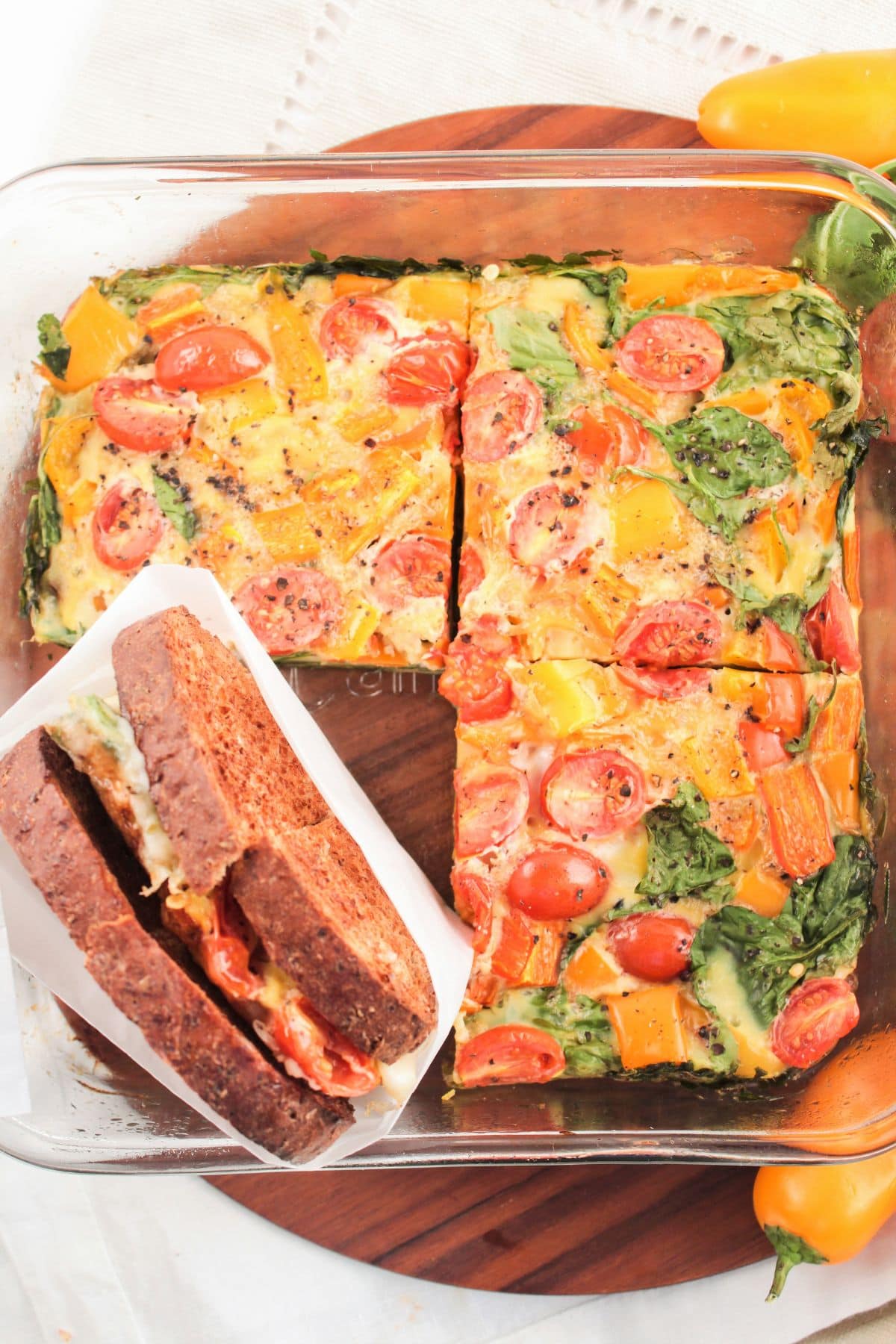 sliced egg bake next to a breakfast sandwich wrapped in parchment paper