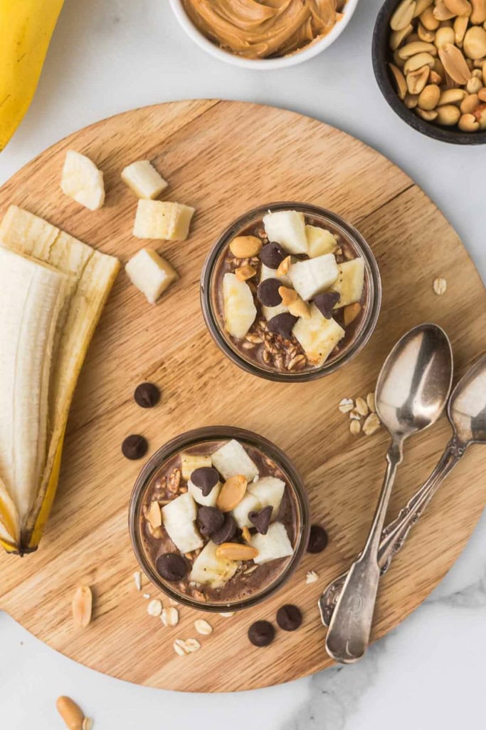 chocolate oatmeal with peanut butter, banana, and chocolate chips in glass jars
