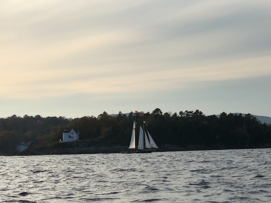 a sailboat and the lighthouse in camden maine