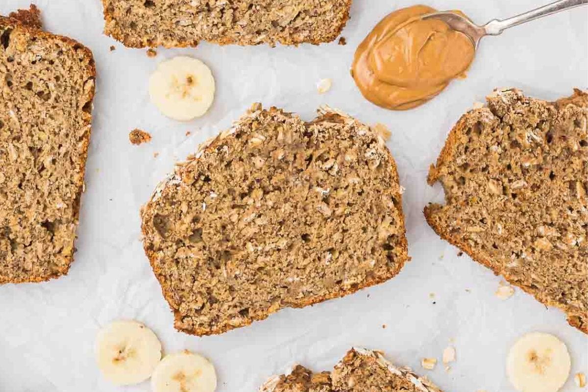 sliced whole wheat banana bread with peanut butter on a spoon beside it