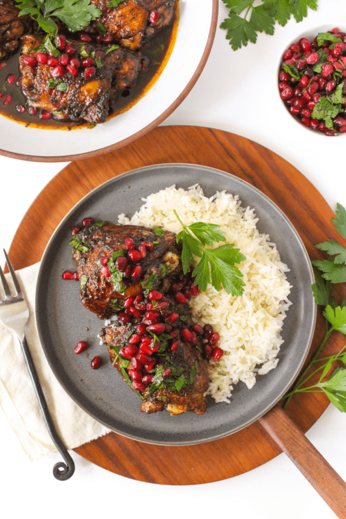 pan seared chicken thighs with pomegranate seeds and rice on a plate